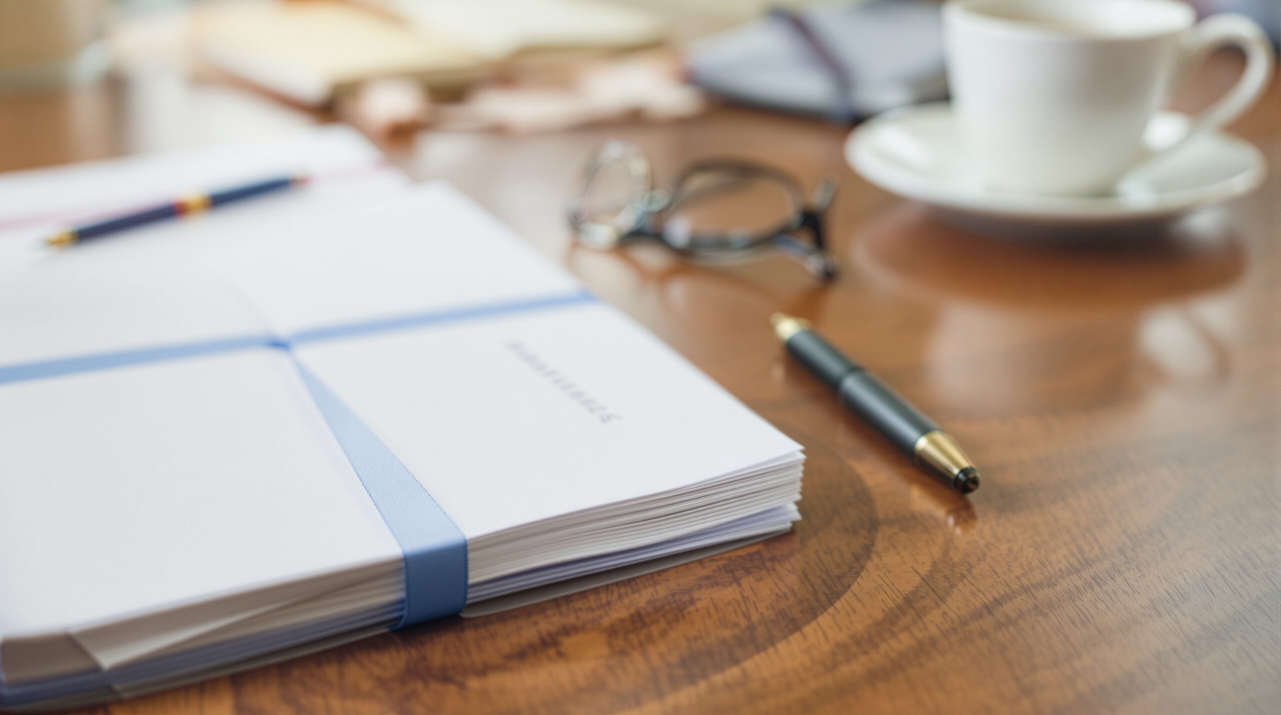 Two stacks of documents with blue and red ribbons on wooden desk, representing different organizational guidelines